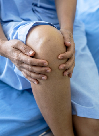 Person in hospital gown clutching knee